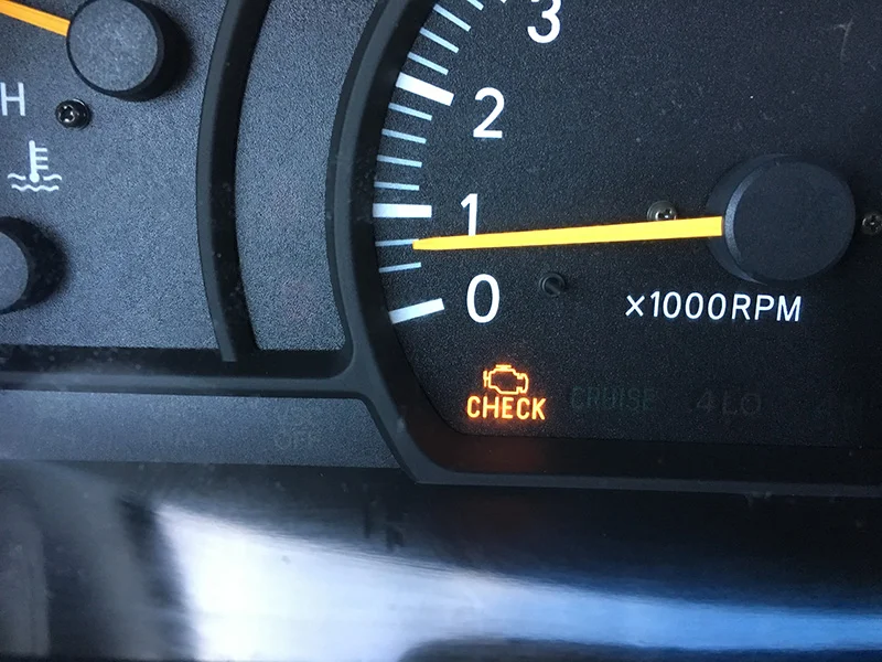 Illuminated check engine light on vehicle dashboard gauge cluster